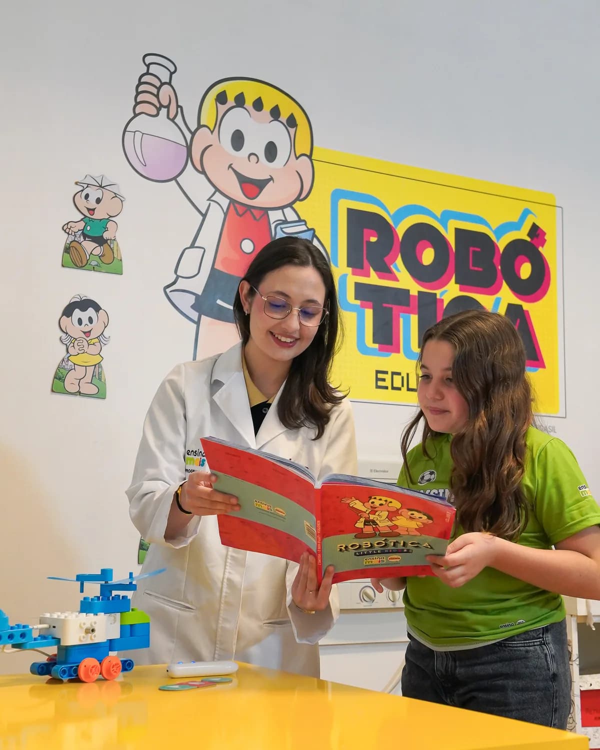 Educadora acompanha uma aluna em uma atividade de leitura e robótica na Ensina Mais